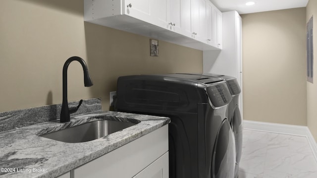 laundry area featuring washer and dryer, sink, and cabinets