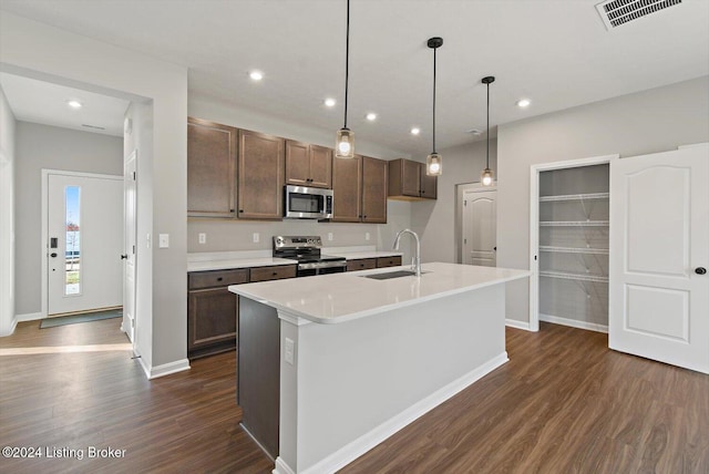 kitchen featuring decorative light fixtures, dark hardwood / wood-style flooring, stainless steel appliances, an island with sink, and sink