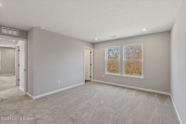 carpeted empty room featuring a textured ceiling