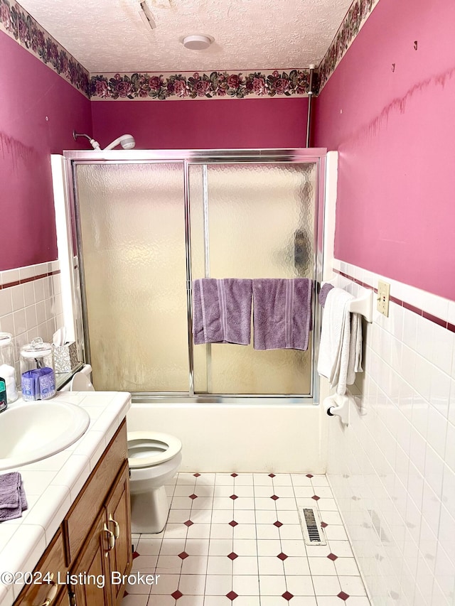 full bathroom featuring tile walls, tile patterned flooring, enclosed tub / shower combo, and a textured ceiling