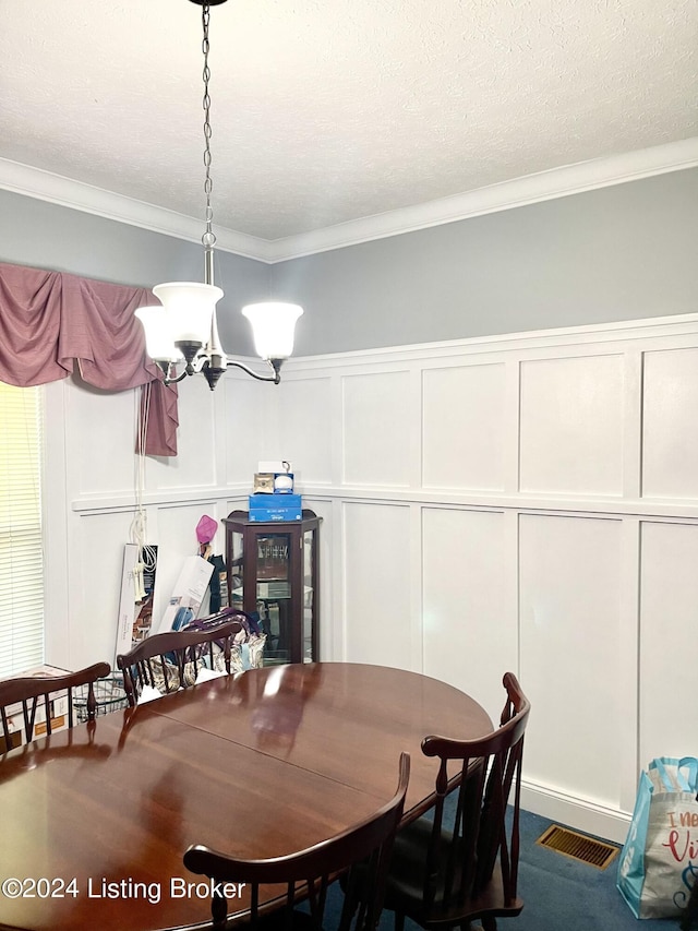 dining space featuring a notable chandelier, ornamental molding, and a textured ceiling