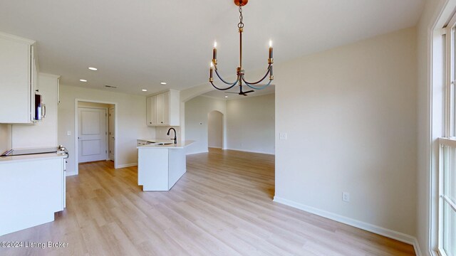 kitchen with pendant lighting, an inviting chandelier, sink, light hardwood / wood-style flooring, and white cabinetry