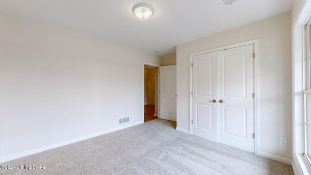 unfurnished bedroom with light carpet and a closet