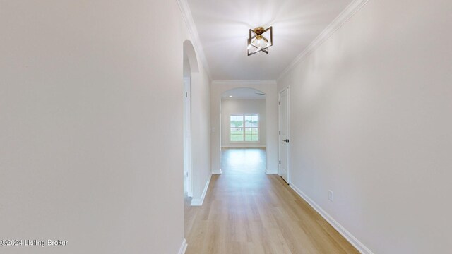 corridor with ornamental molding and light hardwood / wood-style flooring