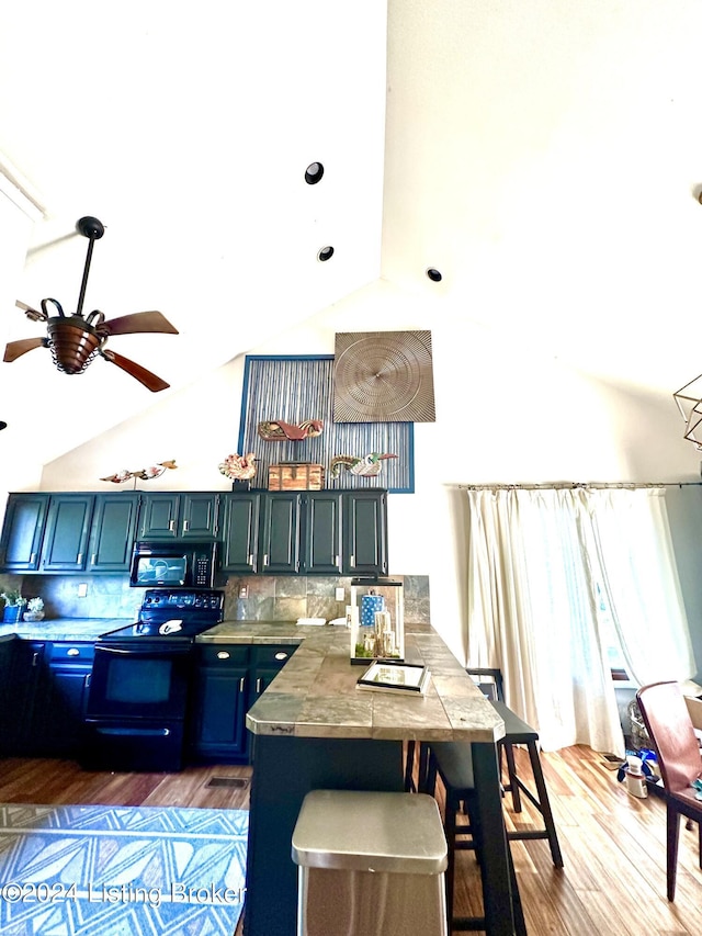 kitchen with dark wood-type flooring, lofted ceiling, ceiling fan, decorative backsplash, and black appliances