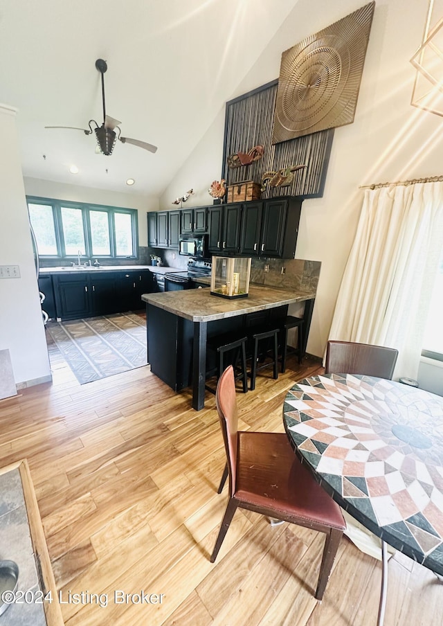 kitchen featuring a kitchen bar, light hardwood / wood-style flooring, kitchen peninsula, ceiling fan, and black appliances