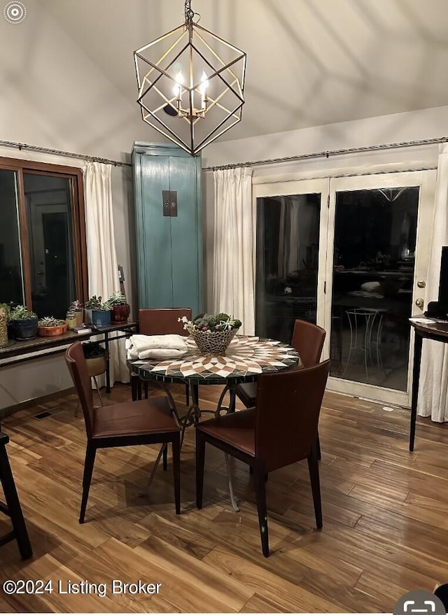 dining space featuring hardwood / wood-style flooring, vaulted ceiling, and a notable chandelier