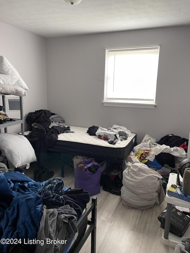 bedroom with light hardwood / wood-style floors and a textured ceiling