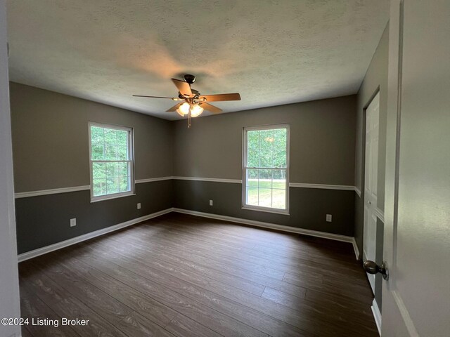 unfurnished room with dark wood-style floors, ceiling fan, and a wealth of natural light