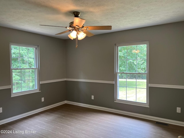 spare room featuring a ceiling fan, wood finished floors, baseboards, and a textured ceiling