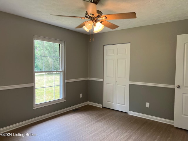 unfurnished room featuring a textured ceiling, visible vents, baseboards, ceiling fan, and wood finished floors