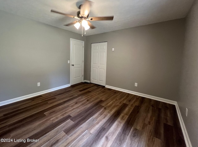 spare room featuring baseboards, dark wood-style floors, and ceiling fan