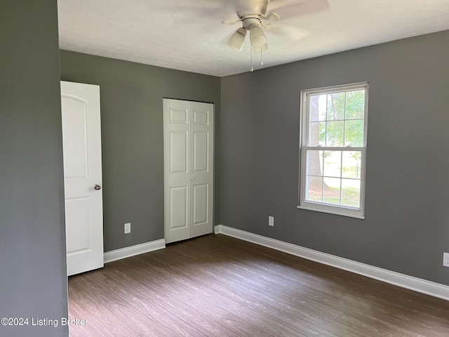 unfurnished bedroom with baseboards, ceiling fan, a closet, and dark wood finished floors