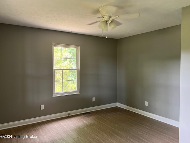 empty room featuring a ceiling fan, dark wood-type flooring, baseboards, and a textured ceiling