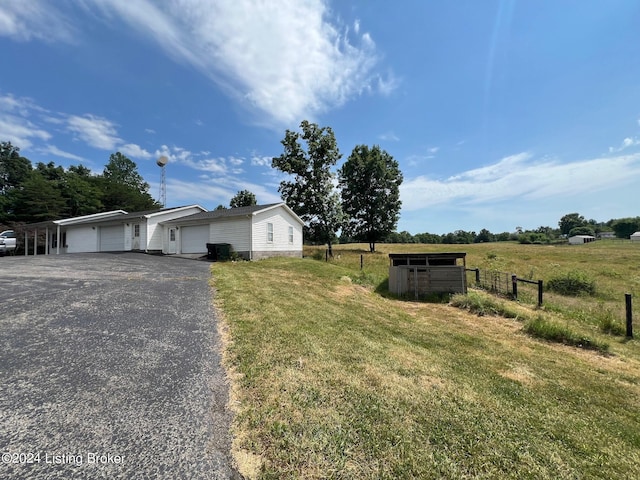 view of front of property featuring driveway, an outbuilding, fence, and a front lawn