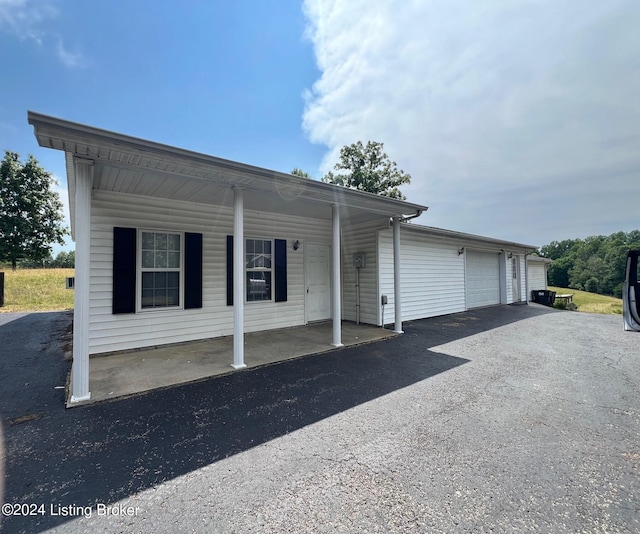 view of front facade with an attached garage, aphalt driveway, and covered porch