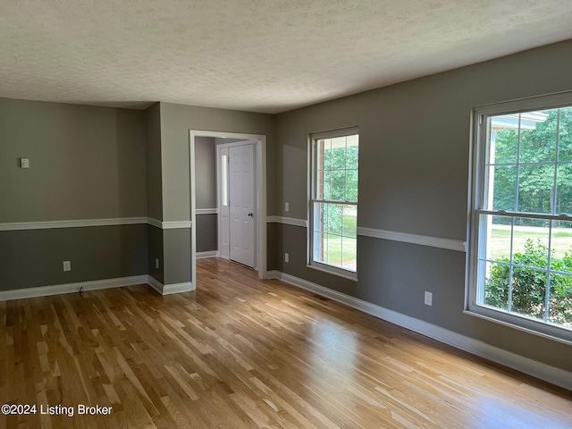 unfurnished room featuring a textured ceiling, baseboards, and wood finished floors