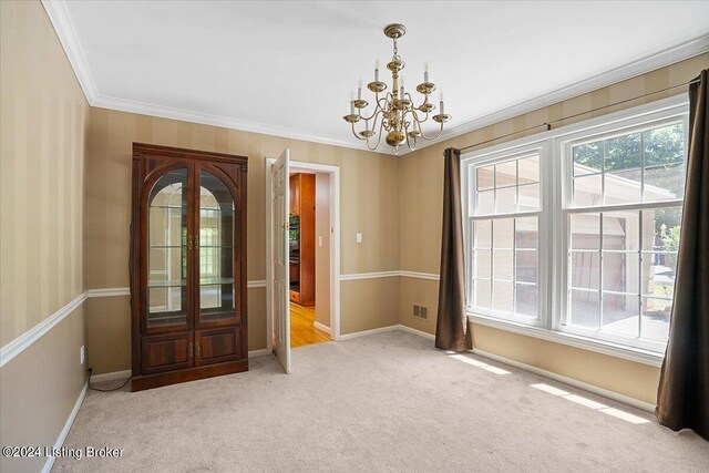 spare room featuring light colored carpet, a chandelier, and ornamental molding