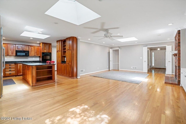 kitchen with a skylight, ceiling fan, a center island, and light hardwood / wood-style floors