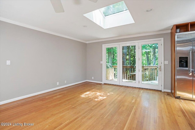 unfurnished room with a skylight, ceiling fan, ornamental molding, and light hardwood / wood-style floors