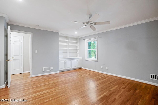 empty room with built in shelves, light hardwood / wood-style flooring, and ornamental molding