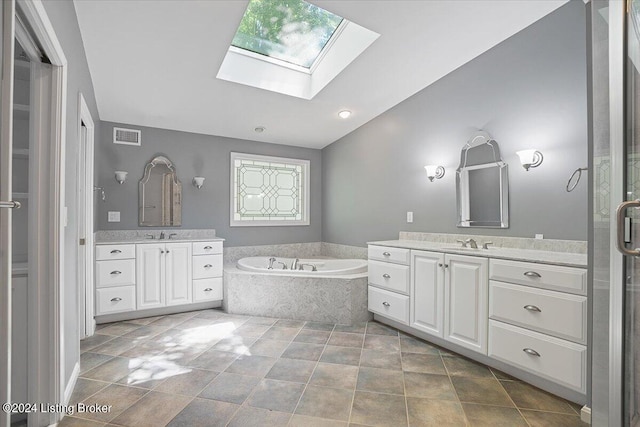 bathroom featuring a skylight, vanity, and a relaxing tiled tub