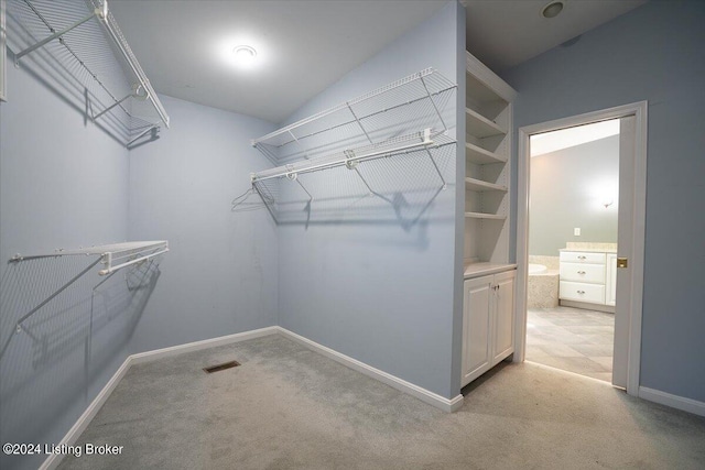 walk in closet featuring light carpet and vaulted ceiling