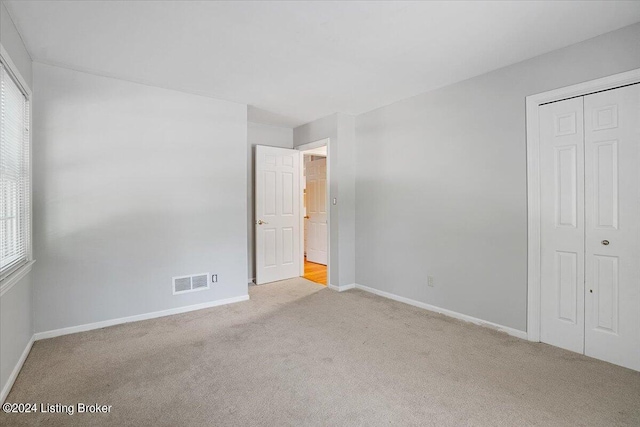 unfurnished bedroom featuring multiple windows, a closet, and light colored carpet