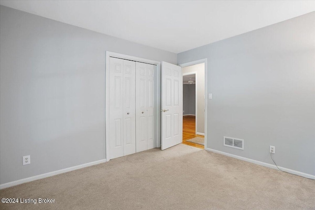 unfurnished bedroom with light carpet and a closet