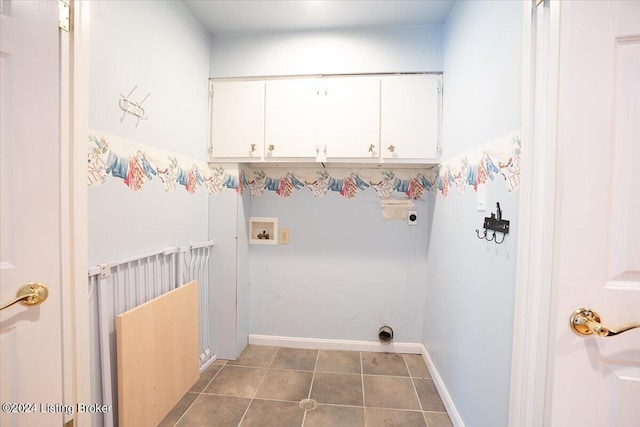 laundry area with electric dryer hookup, hookup for a washing machine, cabinets, and dark tile patterned flooring