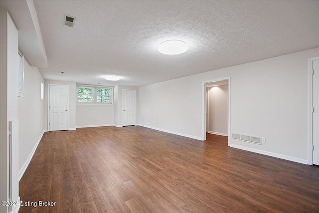 spare room featuring dark hardwood / wood-style flooring and a textured ceiling