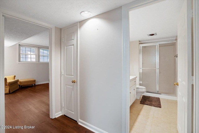 bathroom with hardwood / wood-style floors, a textured ceiling, toilet, vanity, and a shower with shower door