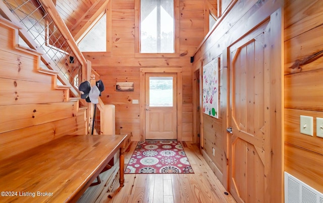 mudroom featuring high vaulted ceiling, wood ceiling, light hardwood / wood-style floors, and wood walls