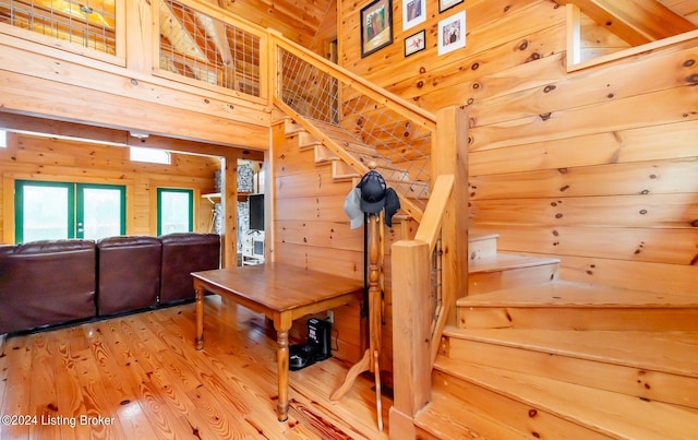 stairway with hardwood / wood-style flooring, a towering ceiling, and wooden walls