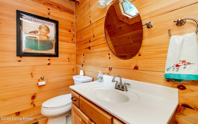 bathroom featuring vanity, wood walls, and toilet