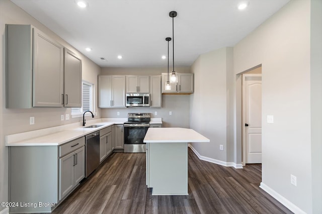 kitchen featuring appliances with stainless steel finishes, a center island, decorative light fixtures, sink, and gray cabinetry