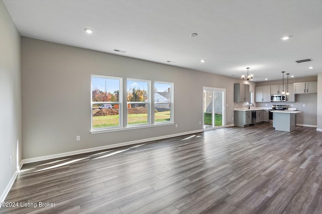 unfurnished living room featuring a notable chandelier, dark hardwood / wood-style floors, and sink