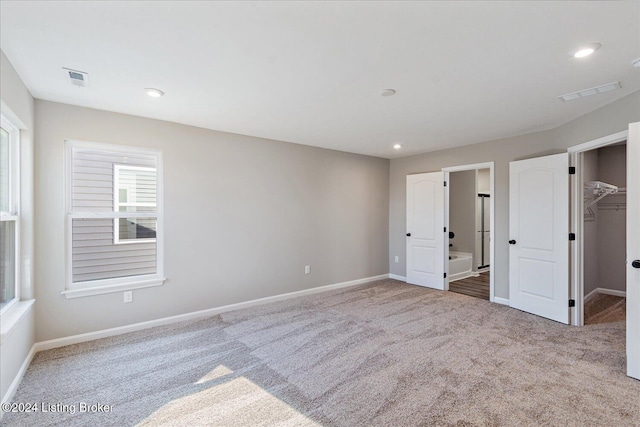 unfurnished bedroom featuring a spacious closet, a closet, and carpet flooring