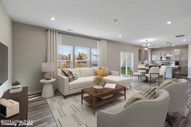 living room with an inviting chandelier and light hardwood / wood-style flooring