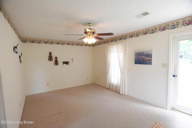 unfurnished room with a textured ceiling, ceiling fan, and light carpet