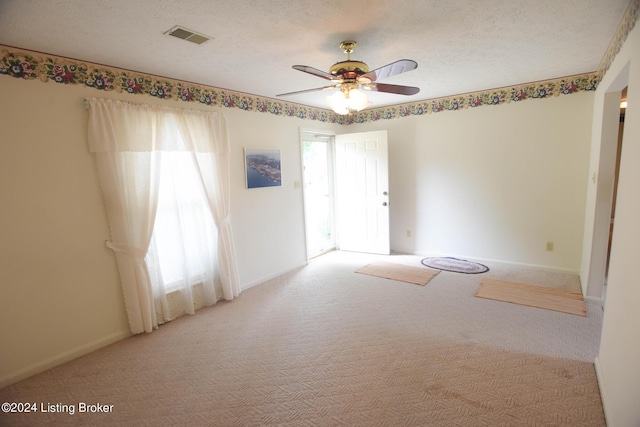 spare room featuring a textured ceiling, light colored carpet, and ceiling fan