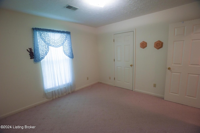 carpeted empty room featuring a textured ceiling