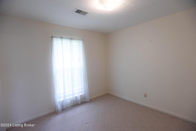 carpeted empty room featuring a textured ceiling