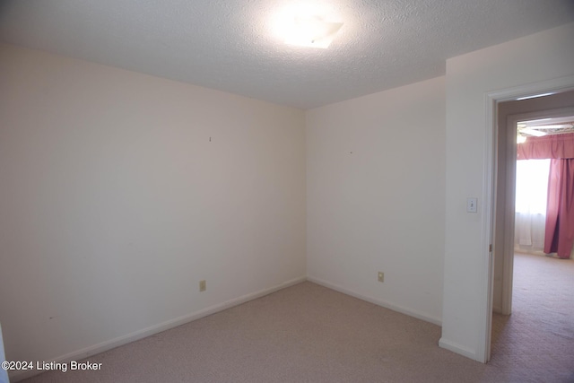 carpeted empty room with a textured ceiling