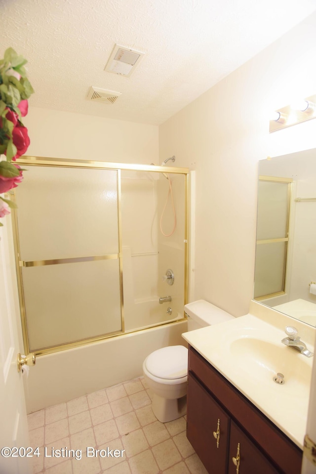 full bathroom with vanity, bath / shower combo with glass door, a textured ceiling, and toilet