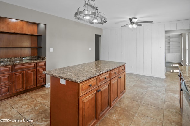 kitchen with built in features, wood walls, stone counters, and a kitchen island