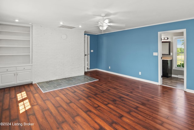 spare room featuring brick wall, dark hardwood / wood-style floors, built in features, and ceiling fan