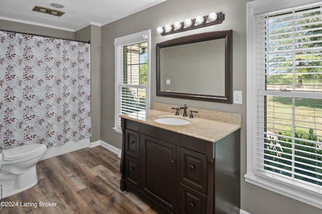 full bathroom with hardwood / wood-style flooring, shower / tub combo, vanity, ornamental molding, and toilet