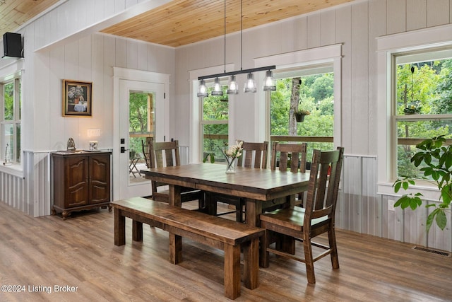 dining space with hardwood / wood-style flooring, wooden ceiling, and wooden walls