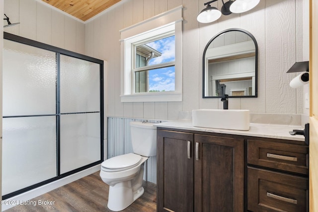 bathroom with an enclosed shower, vanity, wood-type flooring, toilet, and wood walls